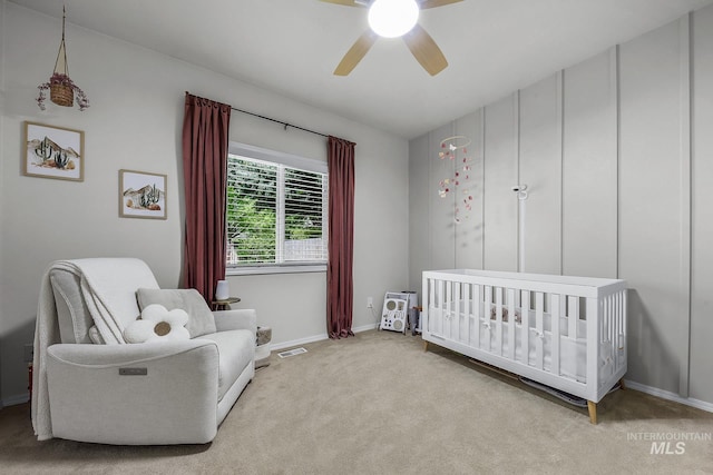 carpeted bedroom featuring a ceiling fan, baseboards, visible vents, and a crib