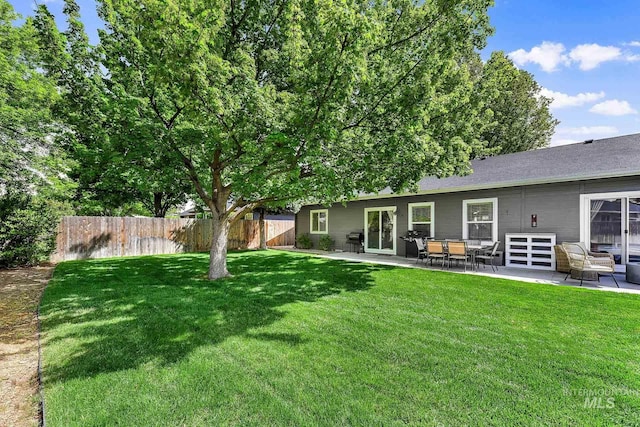 rear view of property with fence, a lawn, and a patio area