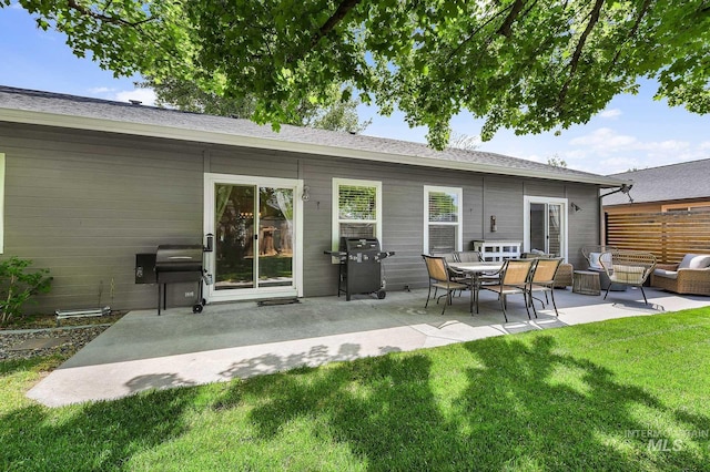 rear view of property with a lawn, fence, an outdoor living space, and a patio area