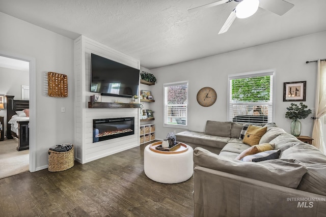 living area featuring ceiling fan, a textured ceiling, a fireplace, wood finished floors, and baseboards