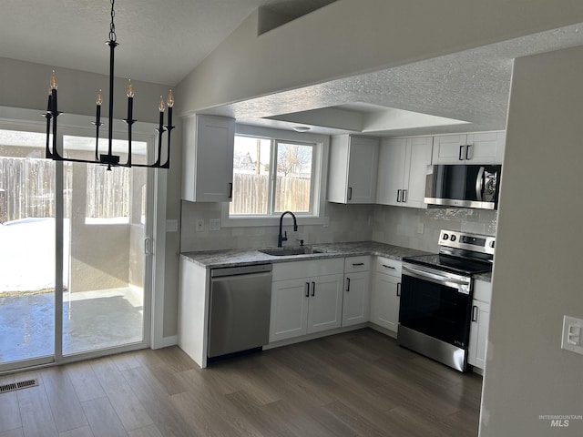 kitchen with appliances with stainless steel finishes, dark hardwood / wood-style floors, decorative light fixtures, sink, and white cabinets