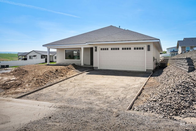 ranch-style house featuring an attached garage, central AC, fence, and concrete driveway
