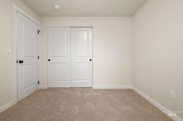 unfurnished bedroom featuring light colored carpet and a closet