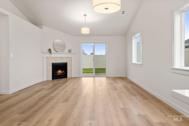 unfurnished living room with lofted ceiling, a fireplace, and light hardwood / wood-style flooring