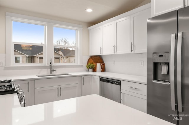 kitchen featuring white cabinets, sink, a wealth of natural light, tasteful backsplash, and stainless steel appliances