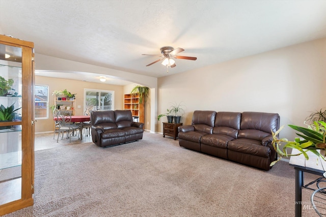 carpeted living room with arched walkways, ceiling fan, a textured ceiling, and baseboards