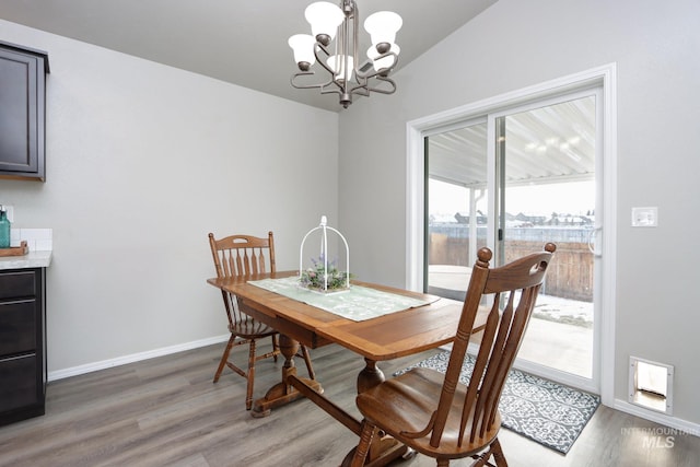 dining room with dark wood-type flooring, a chandelier, and vaulted ceiling