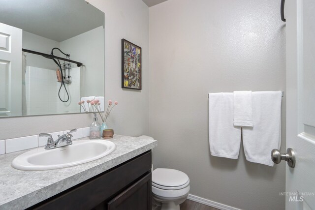 bathroom with vanity, a shower, and toilet