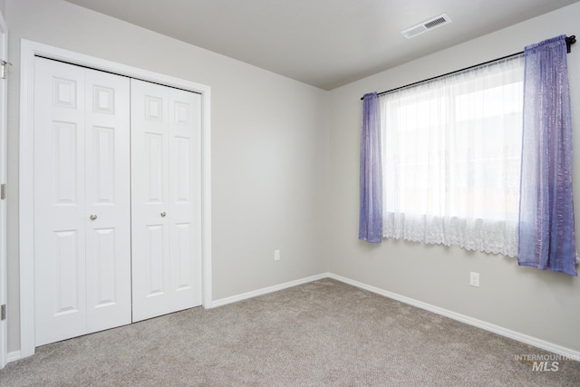 unfurnished bedroom featuring light colored carpet and a closet