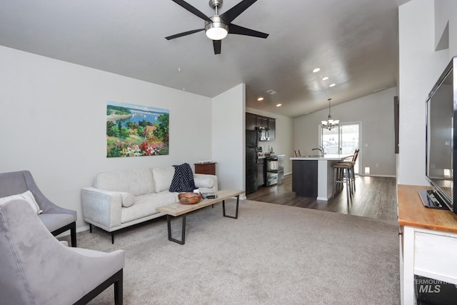 living room with lofted ceiling, dark hardwood / wood-style floors, ceiling fan with notable chandelier, and sink