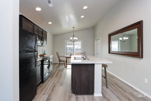 kitchen with dark brown cabinetry, a breakfast bar, sink, an inviting chandelier, and black appliances