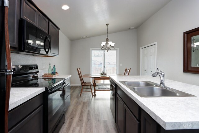 kitchen with decorative light fixtures, lofted ceiling, sink, black appliances, and light hardwood / wood-style flooring