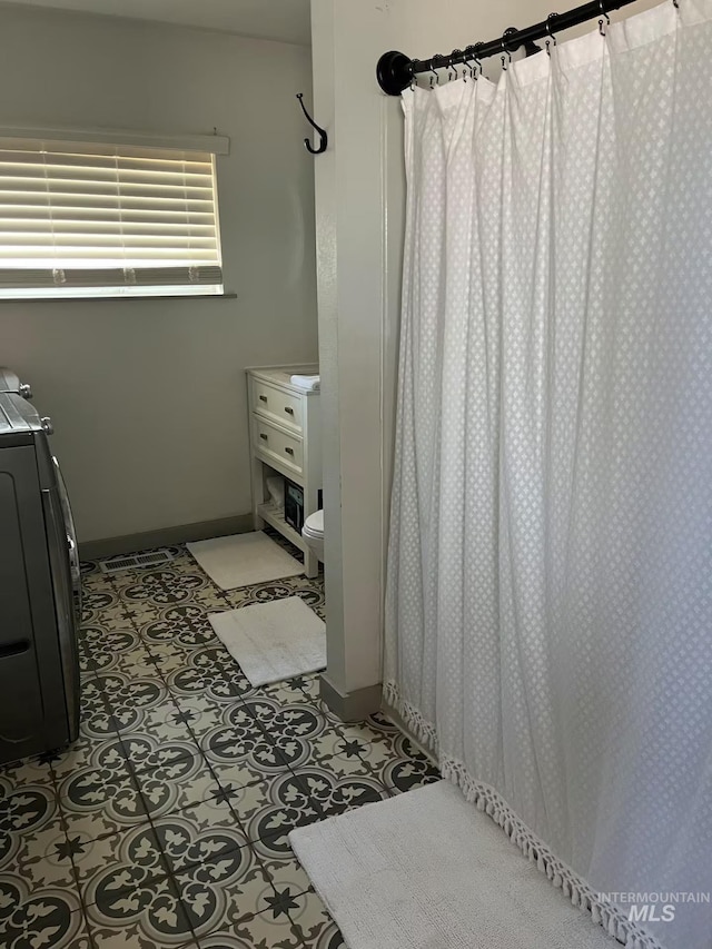 640 Roosevelt Ave, Grand View, ID 83624 - bathroom featuring toilet, a shower with shower curtain, baseboards, and washer / dryer
