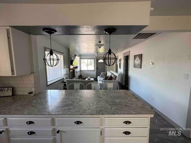 640 Roosevelt Ave, Grand View, ID 83624 - kitchen with pendant lighting, visible vents, open floor plan, decorative backsplash, and white cabinets