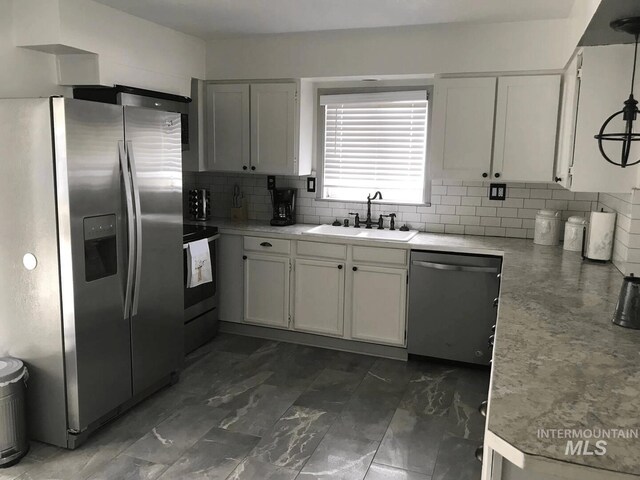 640 Roosevelt Ave, Grand View, ID 83624 - kitchen featuring a sink, stainless steel appliances, white cabinetry, decorative backsplash, and light countertops