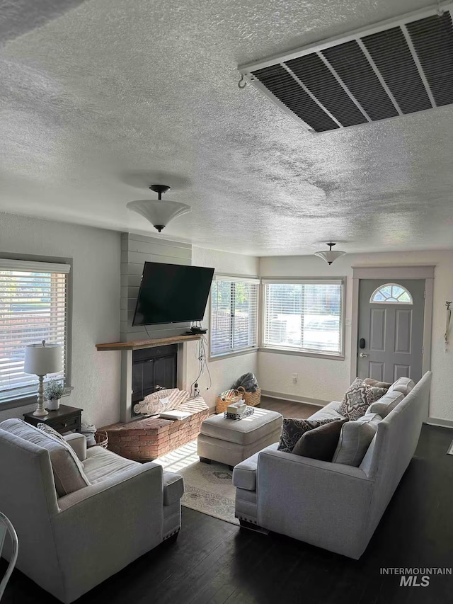 640 Roosevelt Ave, Grand View, ID 83624 - living room with a brick fireplace, visible vents, a textured ceiling, and dark wood-type flooring