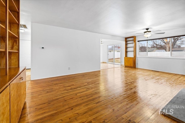 unfurnished living room featuring a ceiling fan and light wood-type flooring