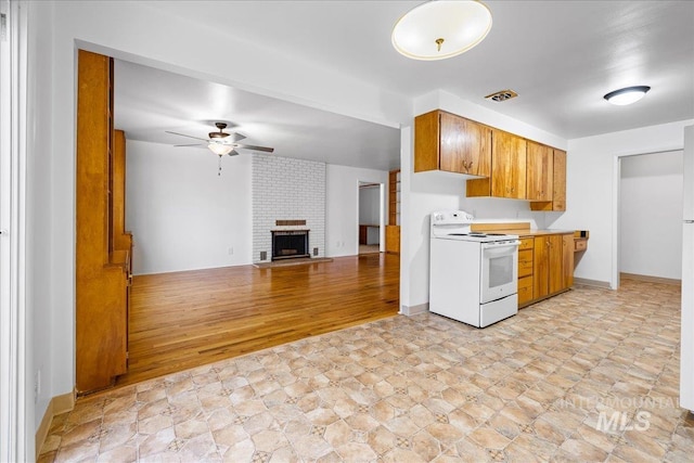 kitchen featuring brown cabinetry, visible vents, a fireplace, ceiling fan, and white electric range