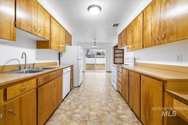 kitchen with white appliances, brown cabinets, visible vents, and a sink