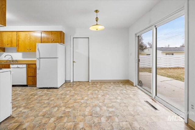 kitchen featuring visible vents, brown cabinets, decorative light fixtures, white appliances, and baseboards