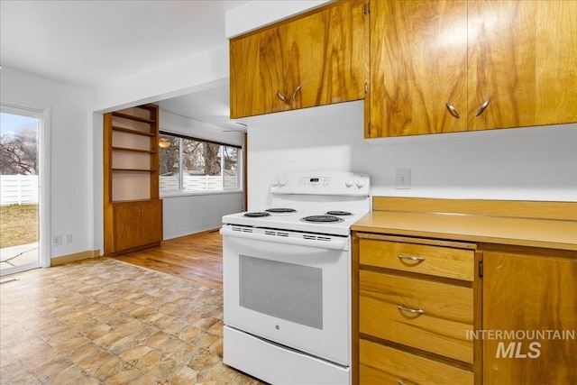 kitchen with light countertops, baseboards, brown cabinets, and white range with electric stovetop