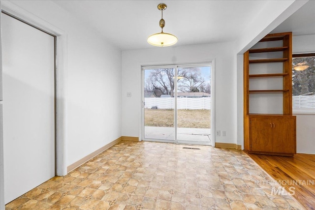 unfurnished dining area with baseboards and stone finish flooring