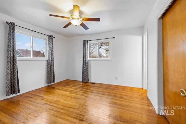 unfurnished room with a wealth of natural light, visible vents, ceiling fan, and light wood finished floors