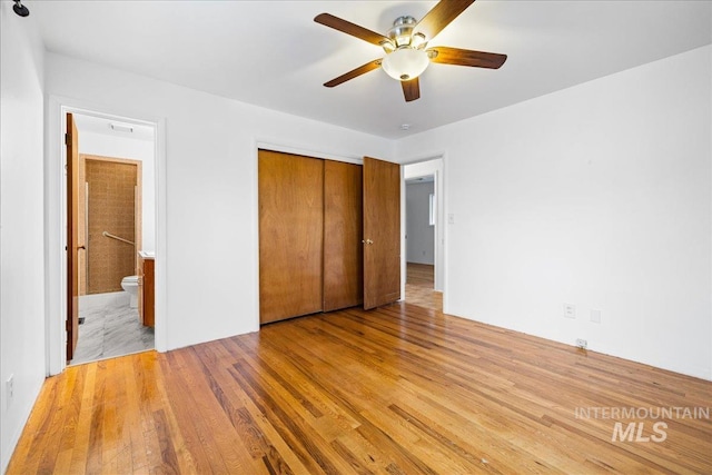 unfurnished bedroom featuring ensuite bathroom, a ceiling fan, a closet, and light wood finished floors