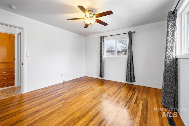 unfurnished room with light wood finished floors, visible vents, and a ceiling fan