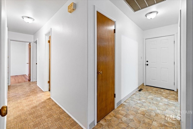 hall featuring baseboards and visible vents