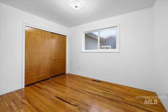 unfurnished bedroom featuring a closet, visible vents, and hardwood / wood-style floors