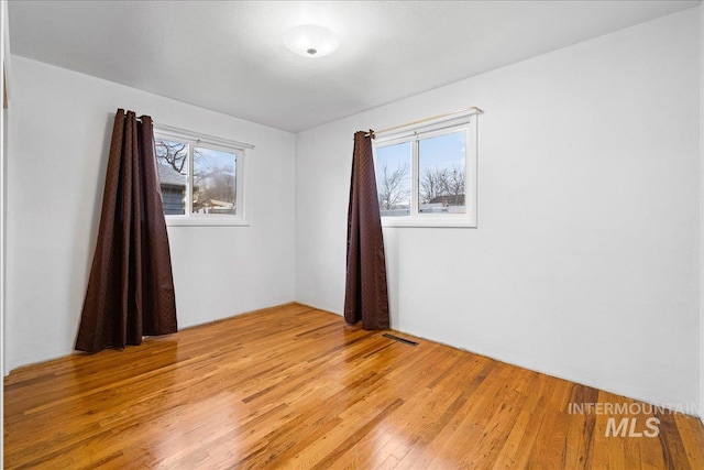 empty room with visible vents, plenty of natural light, and light wood-type flooring