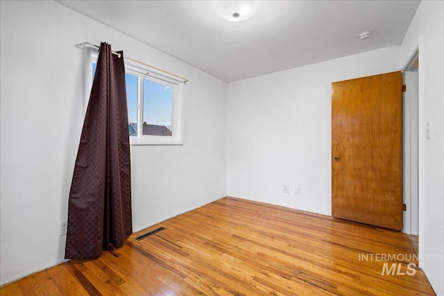 empty room featuring wood finished floors and visible vents