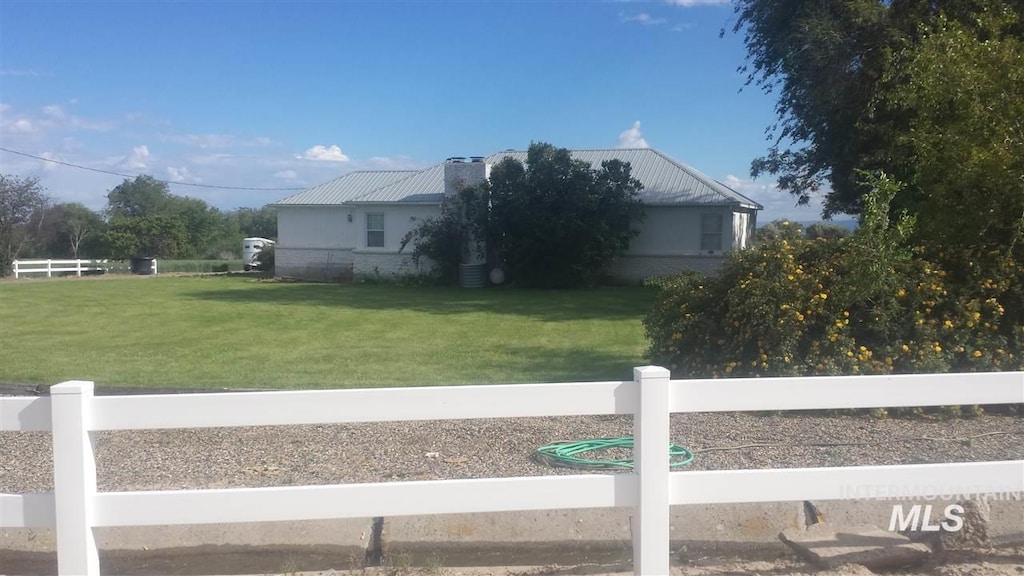 view of home's exterior featuring metal roof, fence private yard, and a lawn