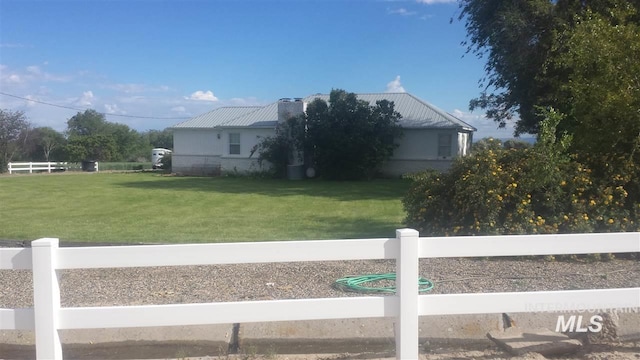 view of home's exterior featuring metal roof, fence private yard, and a lawn