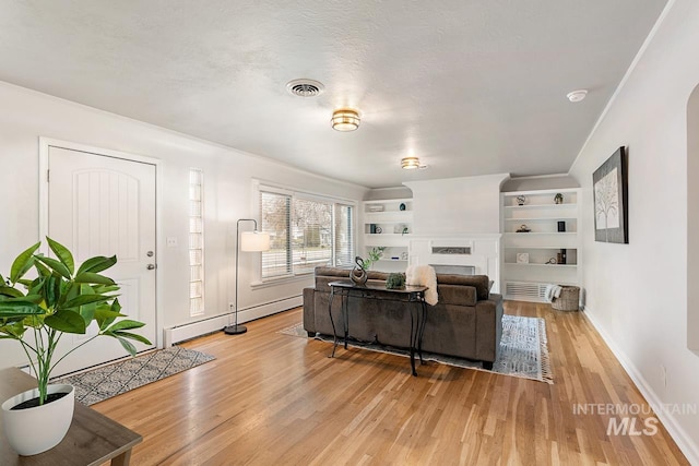 92 N Yale St, Nampa, ID 83651 - living room featuring baseboard heating, light wood-type flooring, a fireplace, baseboards, and visible vents