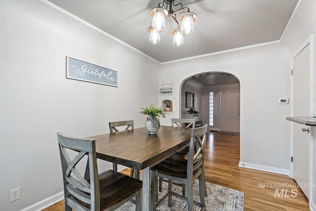 92 N Yale St, Nampa, ID 83651 - dining space featuring light wood finished floors, a chandelier, crown molding, baseboards, and arched walkways