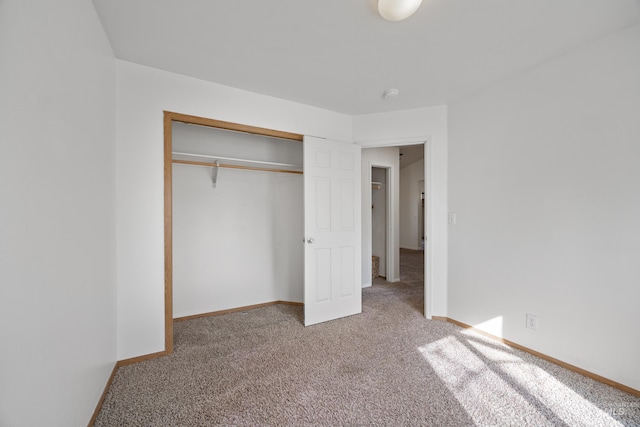 unfurnished bedroom featuring carpet, baseboards, and a closet