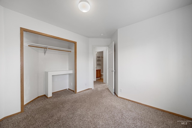 unfurnished bedroom featuring baseboards, carpet floors, and a closet