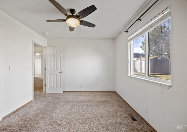 unfurnished room featuring baseboards, visible vents, a ceiling fan, and carpet