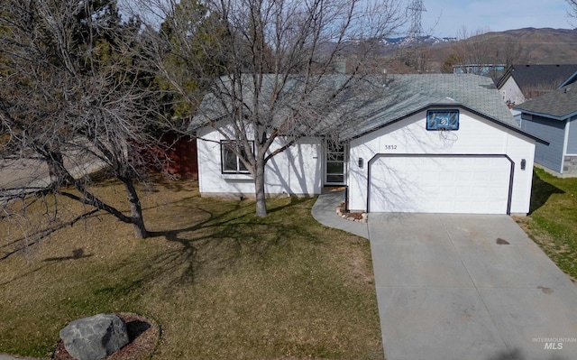 single story home with concrete driveway, a shingled roof, and a front lawn