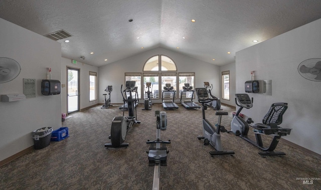 gym featuring visible vents, a textured ceiling, baseboards, and vaulted ceiling