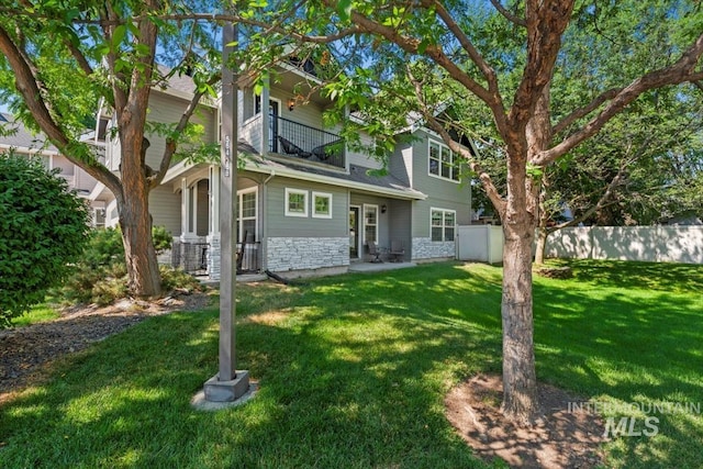 rear view of property with a balcony and a yard