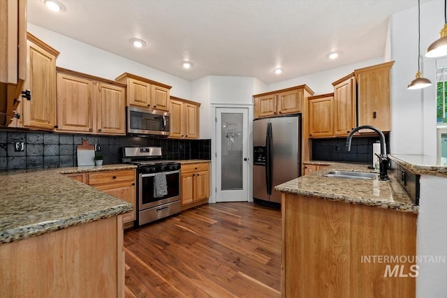 kitchen with sink, dark wood-type flooring, hanging light fixtures, tasteful backsplash, and appliances with stainless steel finishes