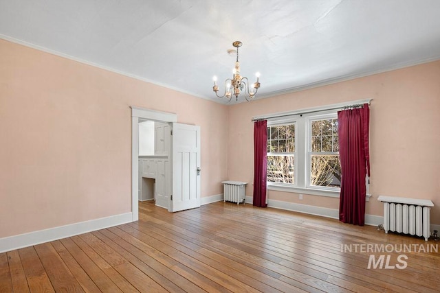 unfurnished room with radiator, an inviting chandelier, baseboards, and hardwood / wood-style flooring