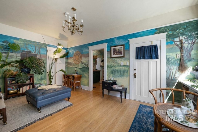sitting room with a notable chandelier, light wood-style floors, and wallpapered walls