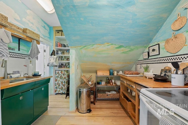 kitchen featuring tasteful backsplash, green cabinets, light wood-type flooring, light countertops, and lofted ceiling