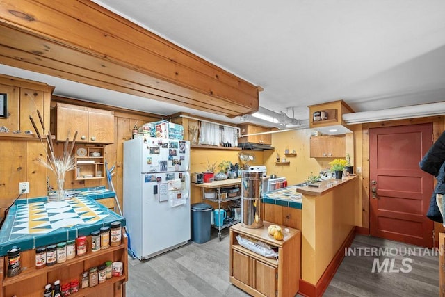 kitchen with light wood-style floors, freestanding refrigerator, tile counters, and open shelves