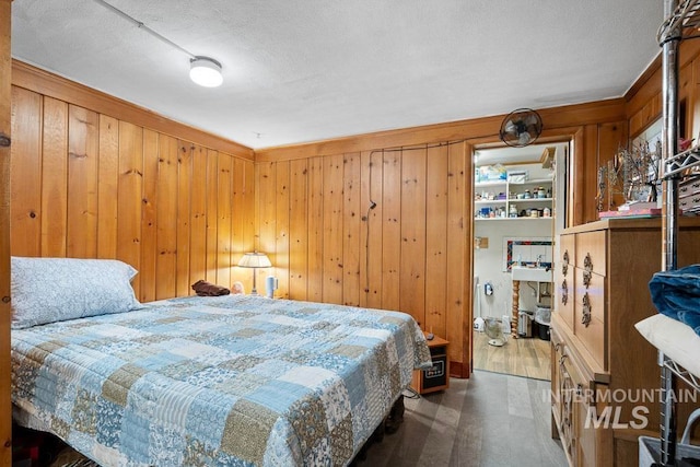 bedroom with wooden walls, wood finished floors, and a textured ceiling