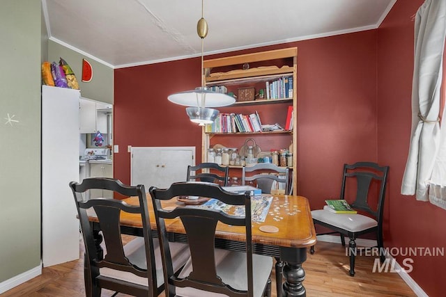 dining space featuring baseboards, crown molding, and wood finished floors